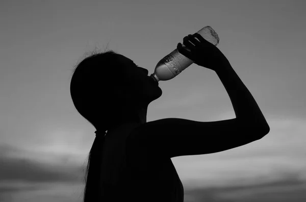 Silhueta de mulher Reidratar e refrescar ao pôr do sol no telhado do edifício, estilo preto e branco — Fotografia de Stock