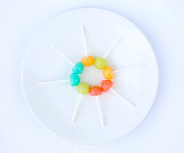 Caramelle lecca lecca in piatto bianco su sfondo bianco — Foto Stock