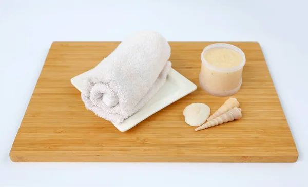 Concepto de spa, toallas y exfoliante de sal sobre tabla de bambú sobre fondo blanco —  Fotos de Stock