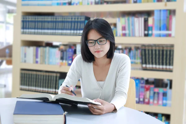 Mujer asiática leyendo un libro en la biblioteca . — Foto de Stock