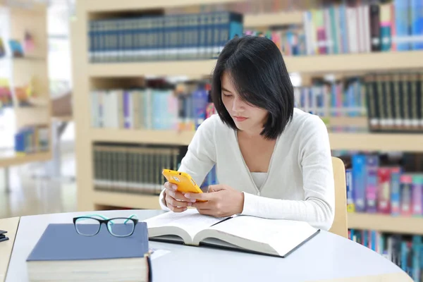 Ασίας φοιτητής χρήση smartphone στη βιβλιοθήκη — Φωτογραφία Αρχείου