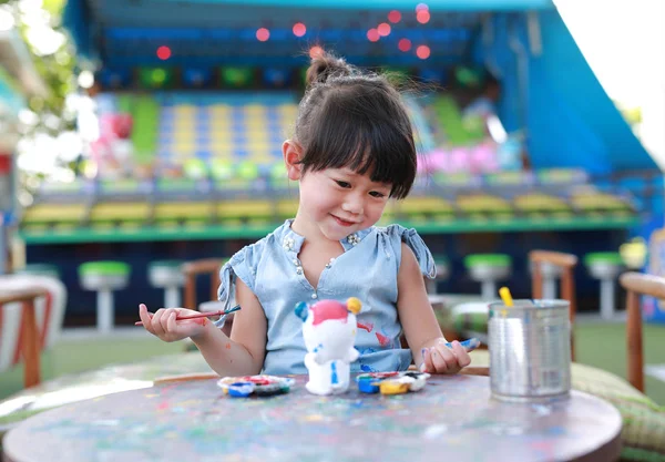 Pintura infantil, Retrato niña divirtiéndose para pintar en estuco muñeca — Foto de Stock