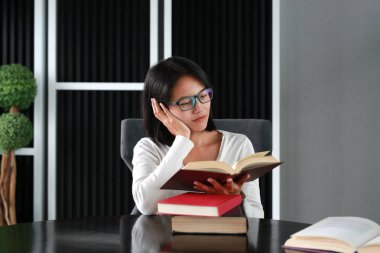 Asyalı kadın kütüphanede kitap okuma.