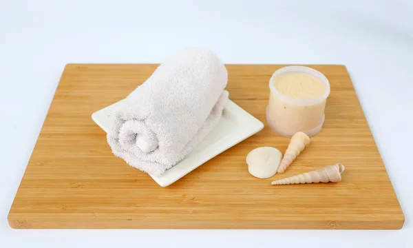 Спа-концепция, полотенца и соляной скраб на бамбуковой доске на белом фоне — стоковое фото