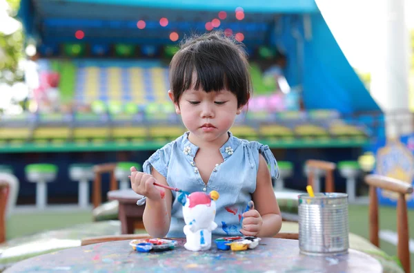 Pintura infantil, Retrato niña divirtiéndose para pintar en estuco muñeca — Foto de Stock