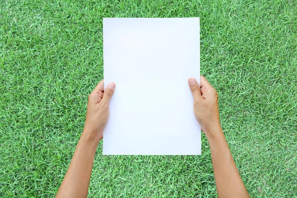 Frau hält Blatt Papier vor grünem Gras-Hintergrund. — Stockfoto