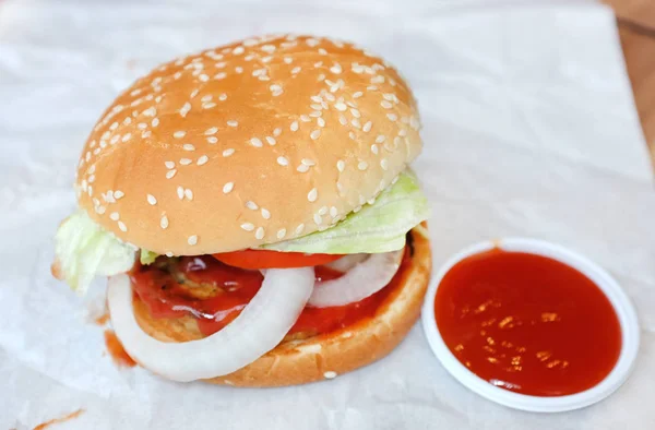 Hambúrguer saboroso com molho de tomate doce em papel — Fotografia de Stock