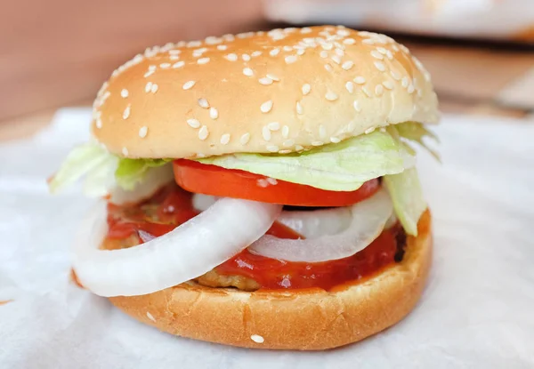 Hambúrguer saboroso com molho de tomate doce em papel — Fotografia de Stock