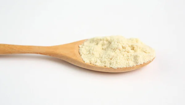 Powdered milk in wooden spoon over white background — Stock Photo, Image