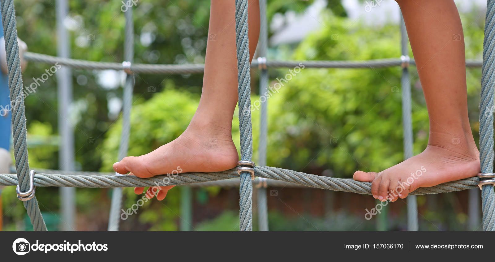 Playing barefoot on a rope climbing equipment playground Stock Photo by
