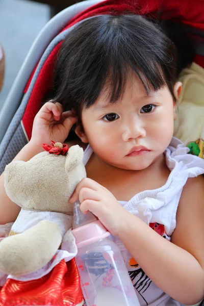 Baby flicka liggande i vaggan med en docka och en flaska mjölk. — Stockfoto