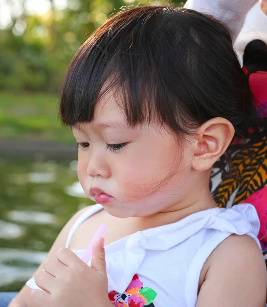 Gadis asia kecil dalam pelukan ibu di taman minum air dengan jerami — Stok Foto