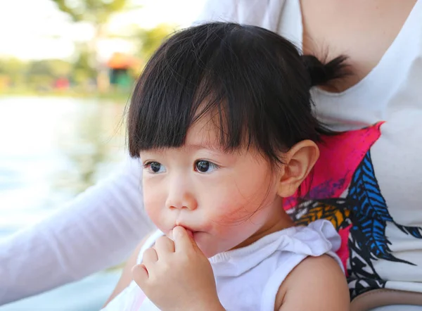 Gadis asia kecil dalam pelukan ibu di taman minum air dengan jerami — Stok Foto
