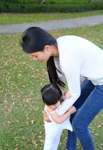 Little asian girl in mother hug at the park — Stock Photo, Image
