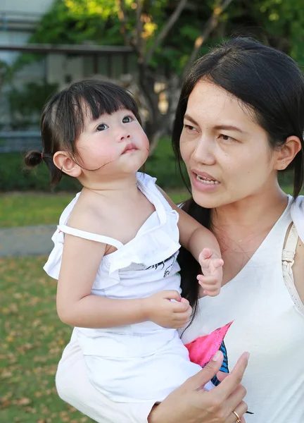 Bliska matka trzyma jej dziecko było śmiałam się i płakałam w parku — Zdjęcie stockowe