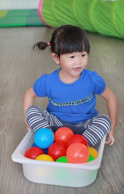 Asyalı çocuk odası plastik tepsisinde renkli topları oynayan çocuk