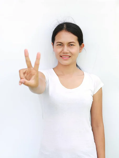Νεαρή γυναίκα της Ασίας στην έκφραση μπλουζάκι δείχνει μια νίκη δύο δακτύλων, επιλεγμένο εστίαση στο πρόσωπό της — Φωτογραφία Αρχείου