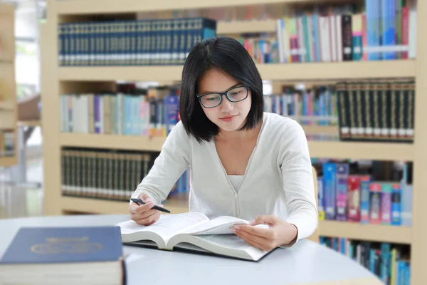 Mujer asiática leyendo un libro en la biblioteca . —  Fotos de Stock