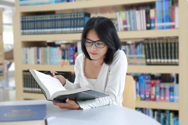 Aziatische vrouw lezen van een boek in de bibliotheek. — Stockfoto