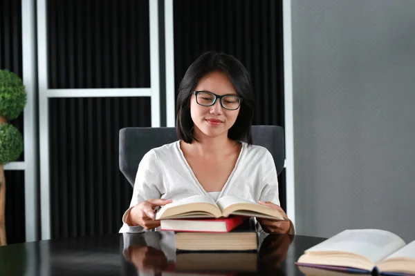 Mujer asiática leyendo un libro en la biblioteca . — Foto de Stock