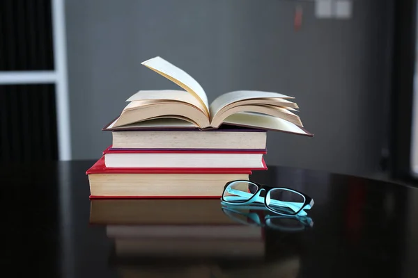 Livro aberto, livros de capa dura e óculos em mesa de madeira. Fundo de educação . — Fotografia de Stock
