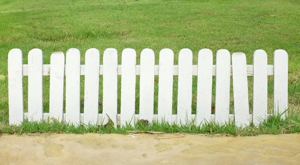 White wood fence and green grass at the garden