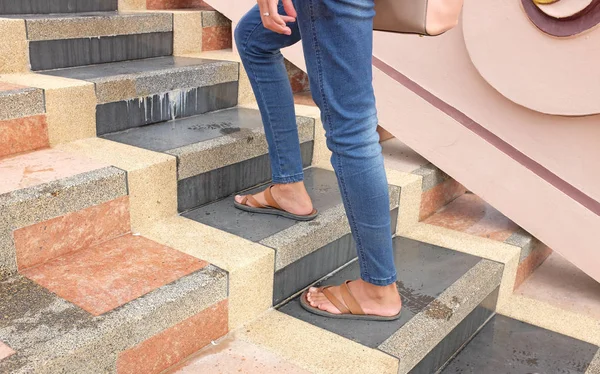 Female with blue jeans and sandal shoes walking upstairs