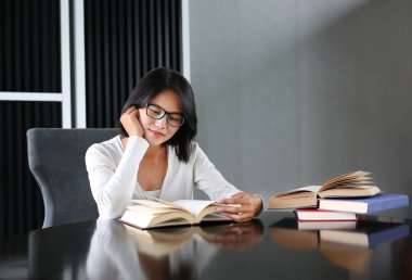 Asyalı kadın kütüphanede kitap okuma.