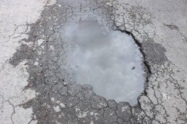 Kötü asphalted yolun büyük bir çukur ile otomobiller için su