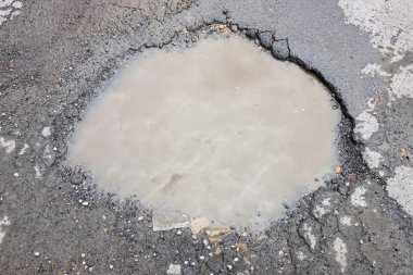 Kötü asphalted yolun büyük bir çukur ile otomobiller için su