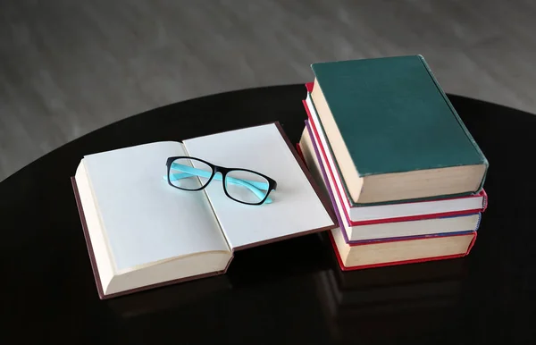 Open boek en hardback boeken op houten tafel in bibliotheek. Opleiding. — Stockfoto