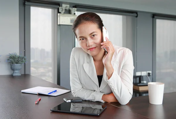 Young businesswoman sitting at the table on workplace in office using the smartphone — Stock Photo, Image
