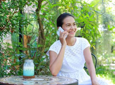 Açık kafede oturan ve telefon kullanarak genç Asyalı kadın