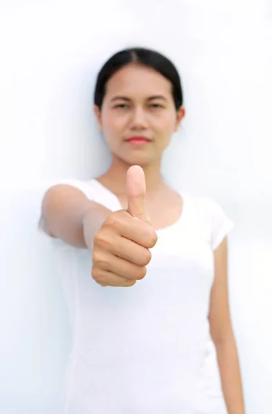 Mulher asiática em camiseta mostrando o polegar no fundo branco, foco selecionado em seu dedo — Fotografia de Stock
