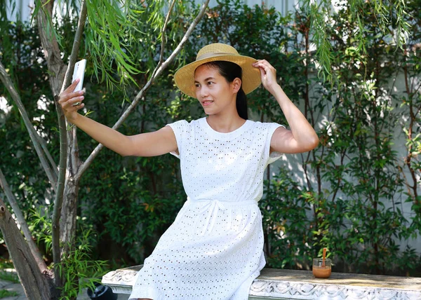 Jovem mulher asiática sentada no café ao ar livre e usando telefone inteligente — Fotografia de Stock