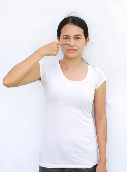 Jovem ásia mulher no t-shirt expressão ponto e tocando dedo no ela nariz — Fotografia de Stock