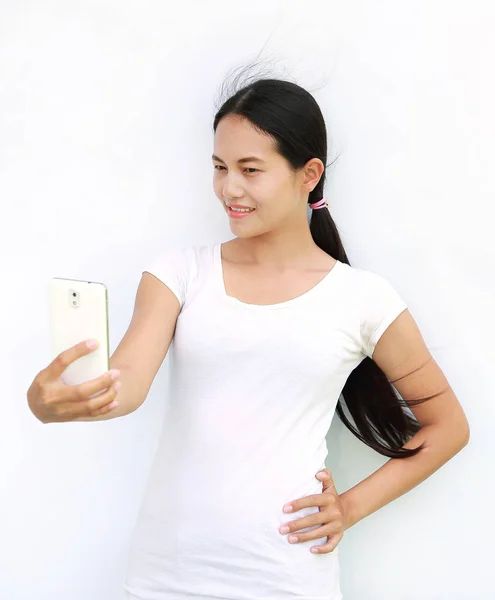 Asiatisk tjej att ta bilder av sig själv genom mobilen på vit bakgrund — Stockfoto