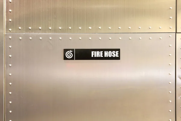 Etiqueta de mangueira de incêndio contra parede de metal — Fotografia de Stock