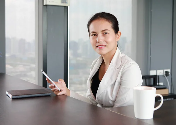 Young businesswoman sitting at the table on workplace in office using the telephone — Stock Photo, Image