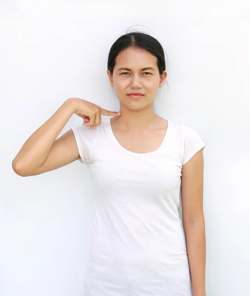 Молодая азиатка в футболке с выражением лица указывает на шею — стоковое фото
