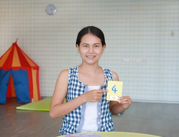 Aziatische vrouw Toon de nummer vier op flash-kaart voor de ontwikkeling van de hersenen van het recht op de Kid-speelkamer — Stockfoto