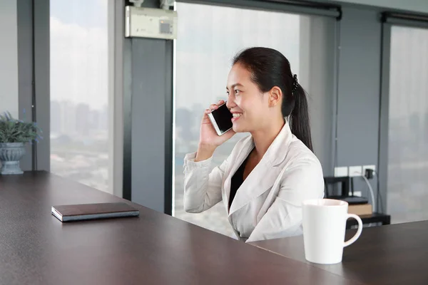 Ung affärsman som sitter på stolen på arbetsplatsen i office via telefon — Stockfoto