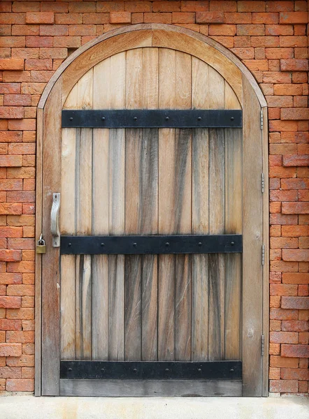 Porta de arco de madeira no fundo da parede de tijolo vermelho — Fotografia de Stock
