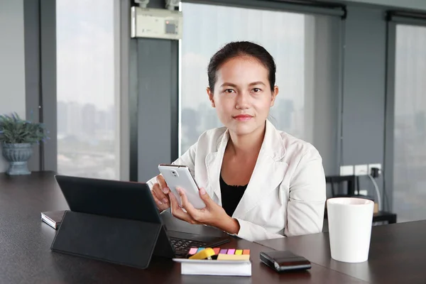 Young businessman sitting at the chair on workplace in office using the smartphone — Stock Photo, Image