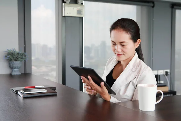 Młoda kobieta interesu siedzi przy stole w miejscu pracy w biurze z graniem tablet — Zdjęcie stockowe