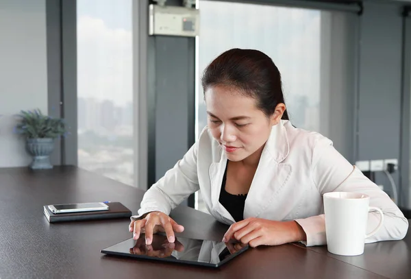 Młoda kobieta interesu siedzi przy stole w miejscu pracy w biurze z graniem tablet — Zdjęcie stockowe