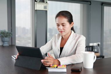 Dizüstü bilgisayar ile office işyerinde masada oturan genç iş kadını