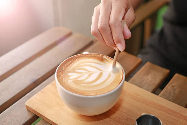 Café con leche caliente con patrón de corazones y jarabe en la mesa de madera — Foto de Stock