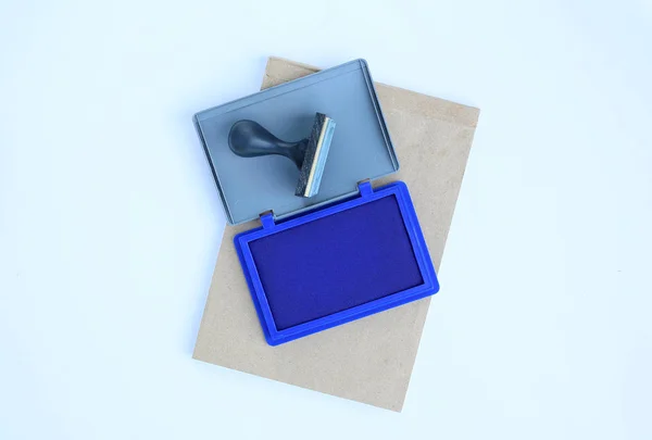 Sello de goma y cartuchos de tinta azul sobre libro marrón sobre fondo blanco . —  Fotos de Stock