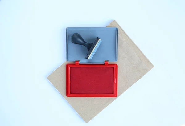 Timbro di gomma e cartucce di inchiostro rosso su libro marrone su sfondo bianco . — Foto Stock